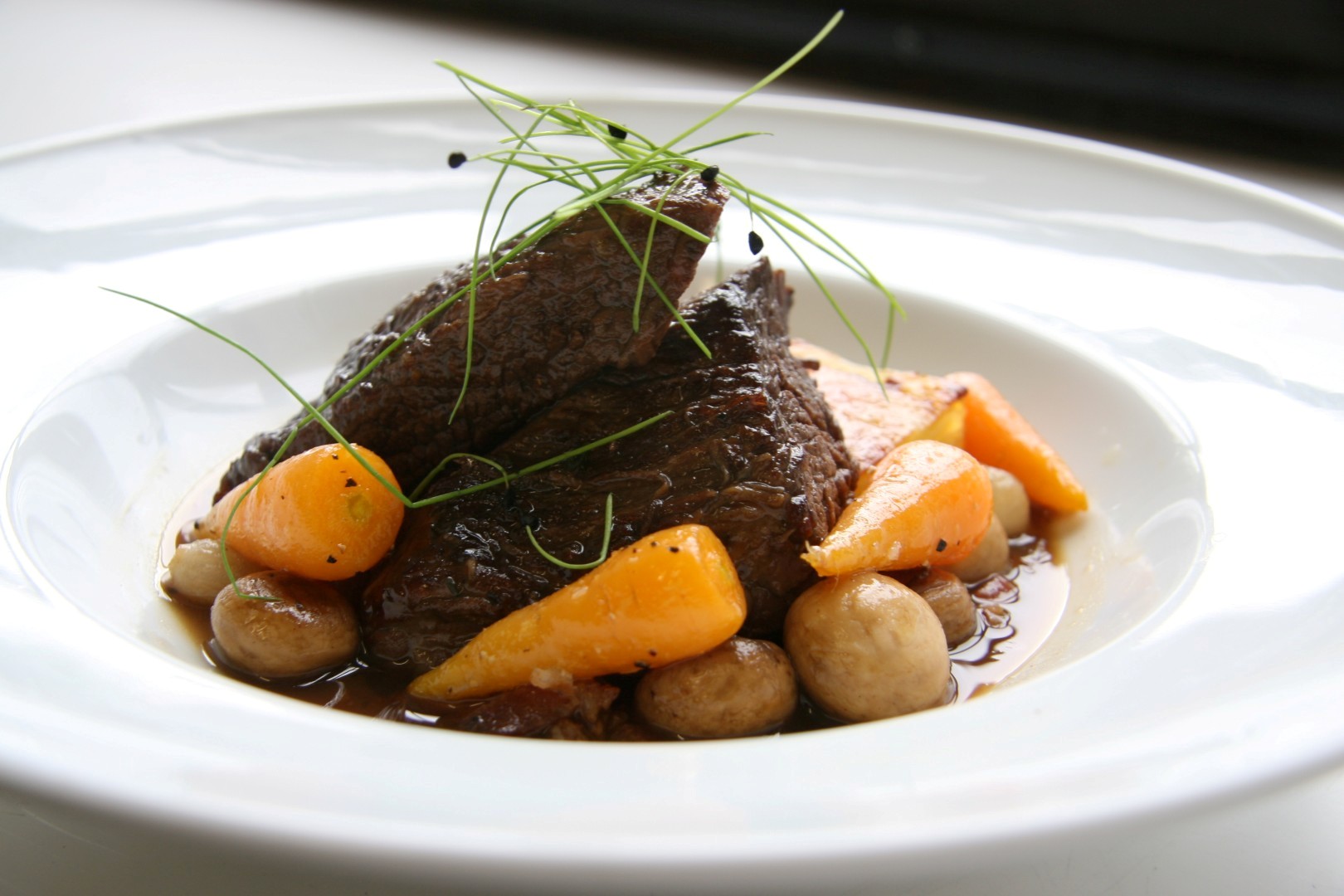 Sticky braised beef with potato and parsnip puree, roasted root vegetables, caramelised shallot and parsley oil