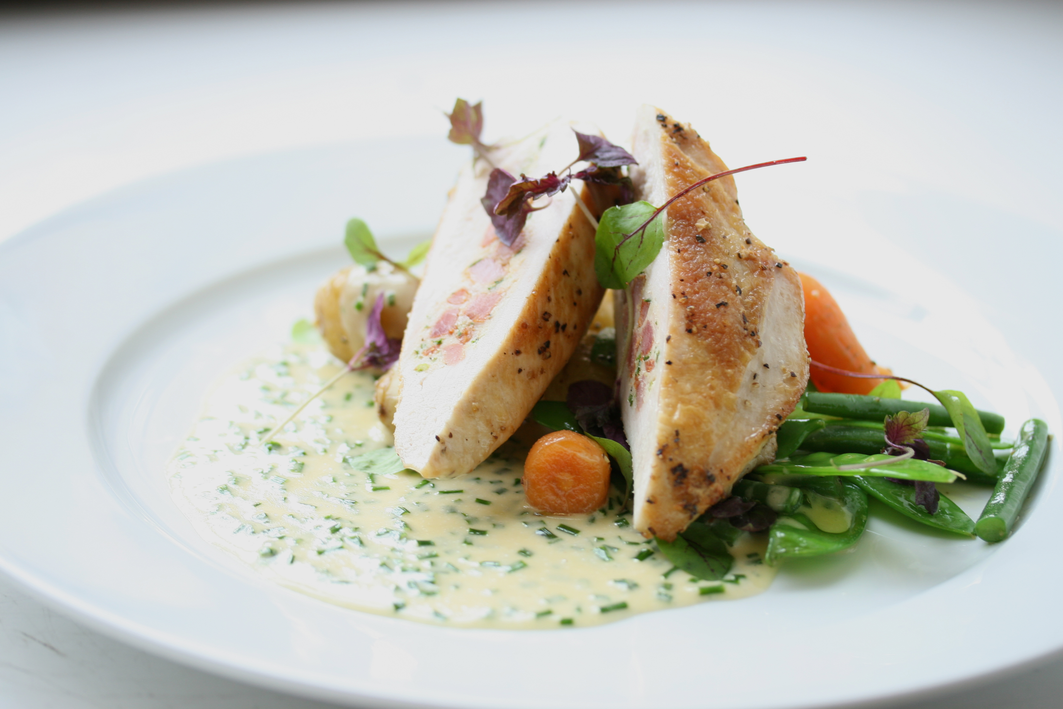 Breast of chicken stuffed with tarragon and pancetta with a chive velouté, new potatoes and seasonal vegetables